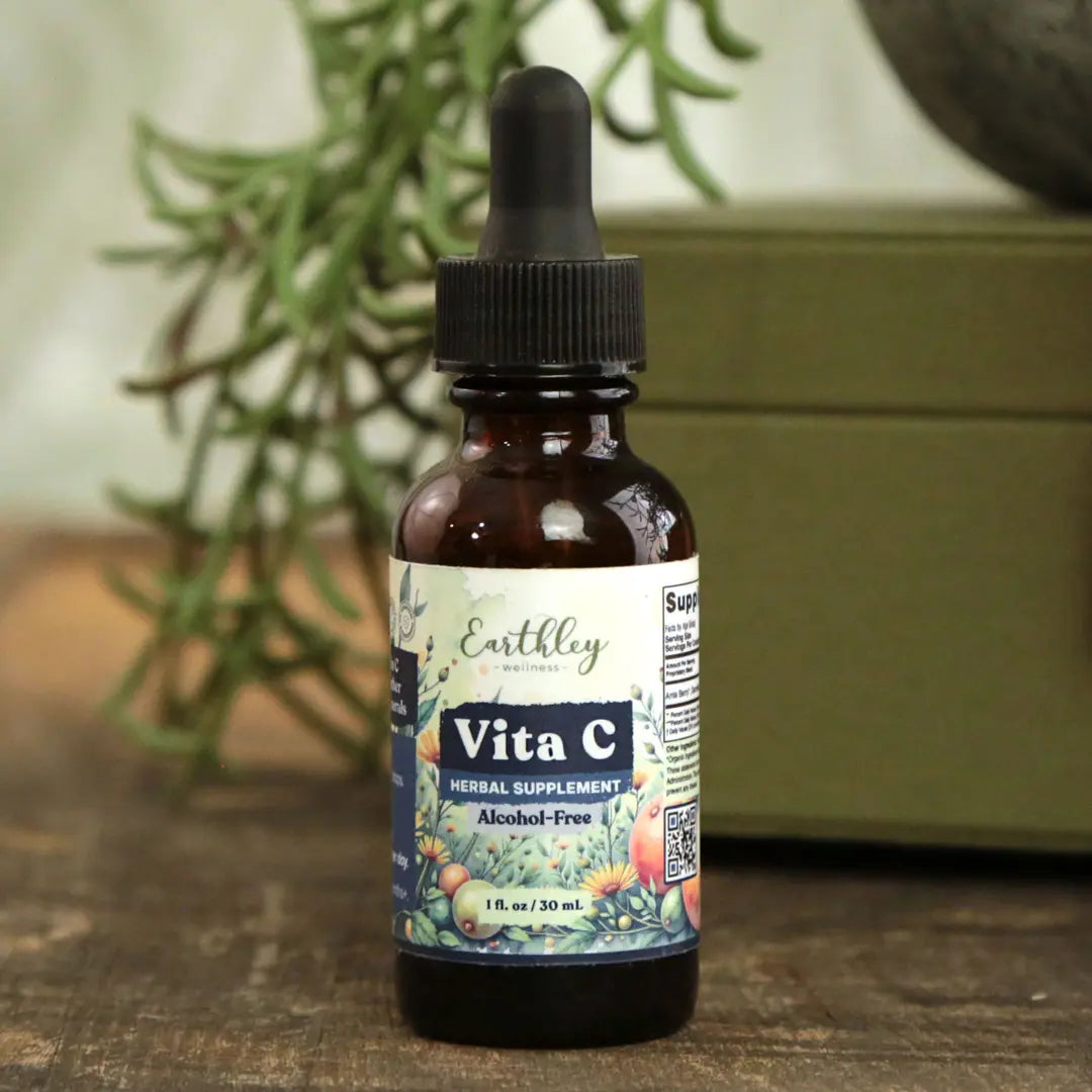 Bottle of Earthly Vita C supplement with dropper on a wooden surface with plants in the background