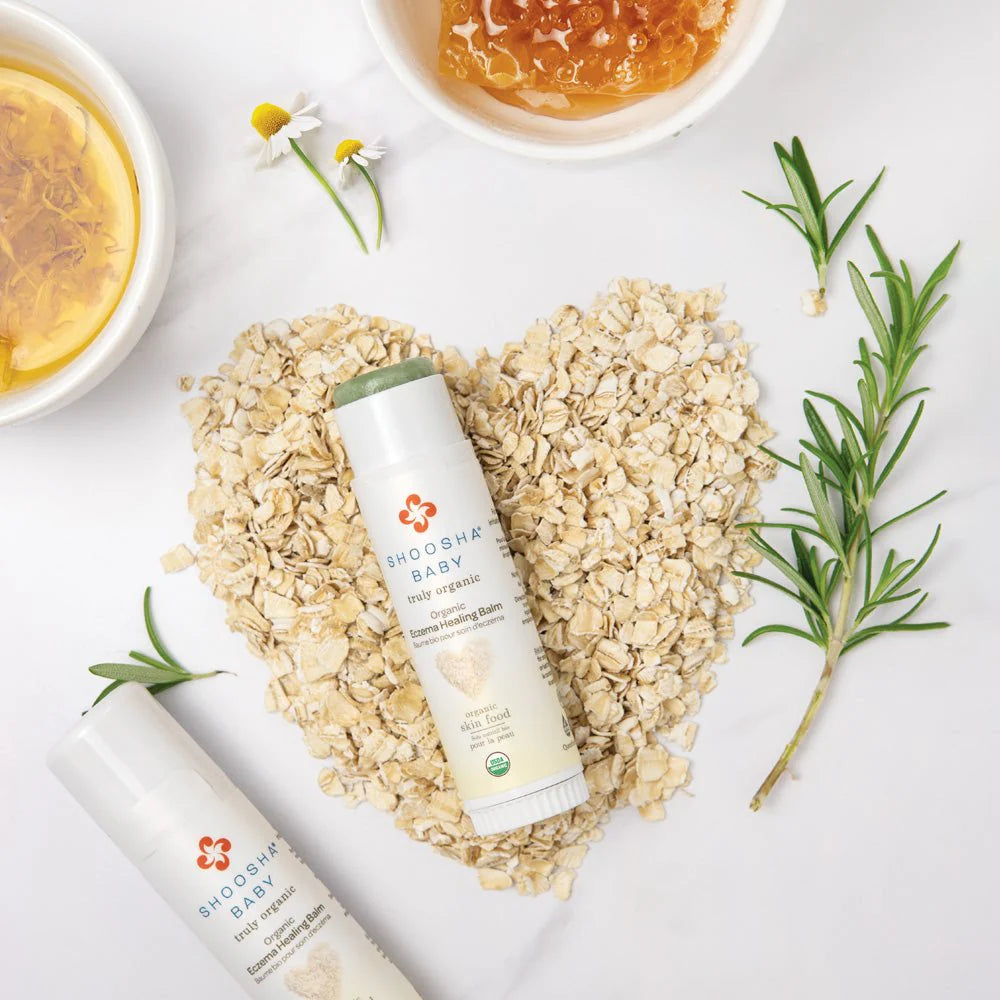 Two skincare bottles on a heart-shaped bed of oats, surrounded by chamomile, rosemary, and honey. Elements convey natural and soothing themes.