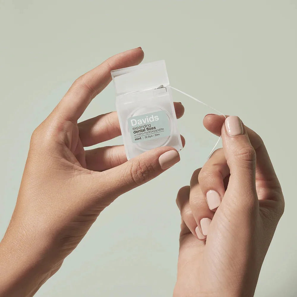 Person holding a package of Davids dental floss against a light background