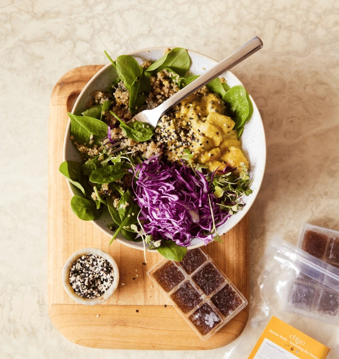 Salad with purple cabbage and a bowl of dressing on a wooden board.