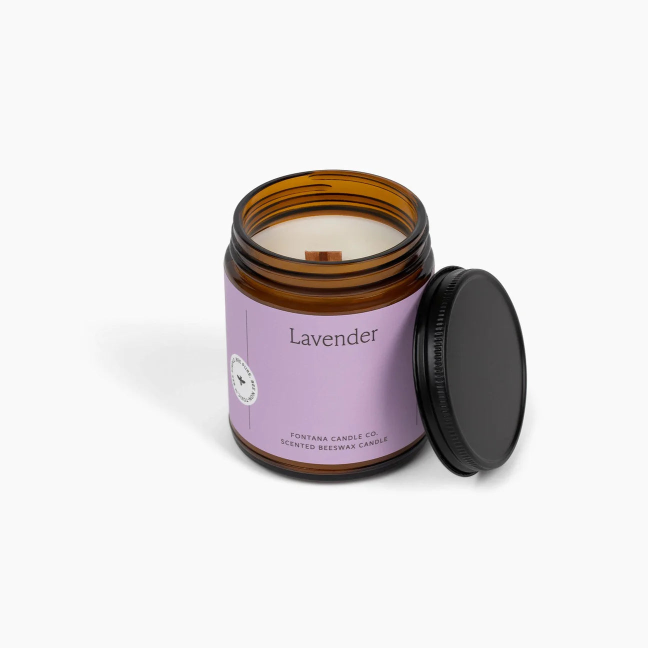 Lavender candle in an amber glass jar with a purple label on a white background